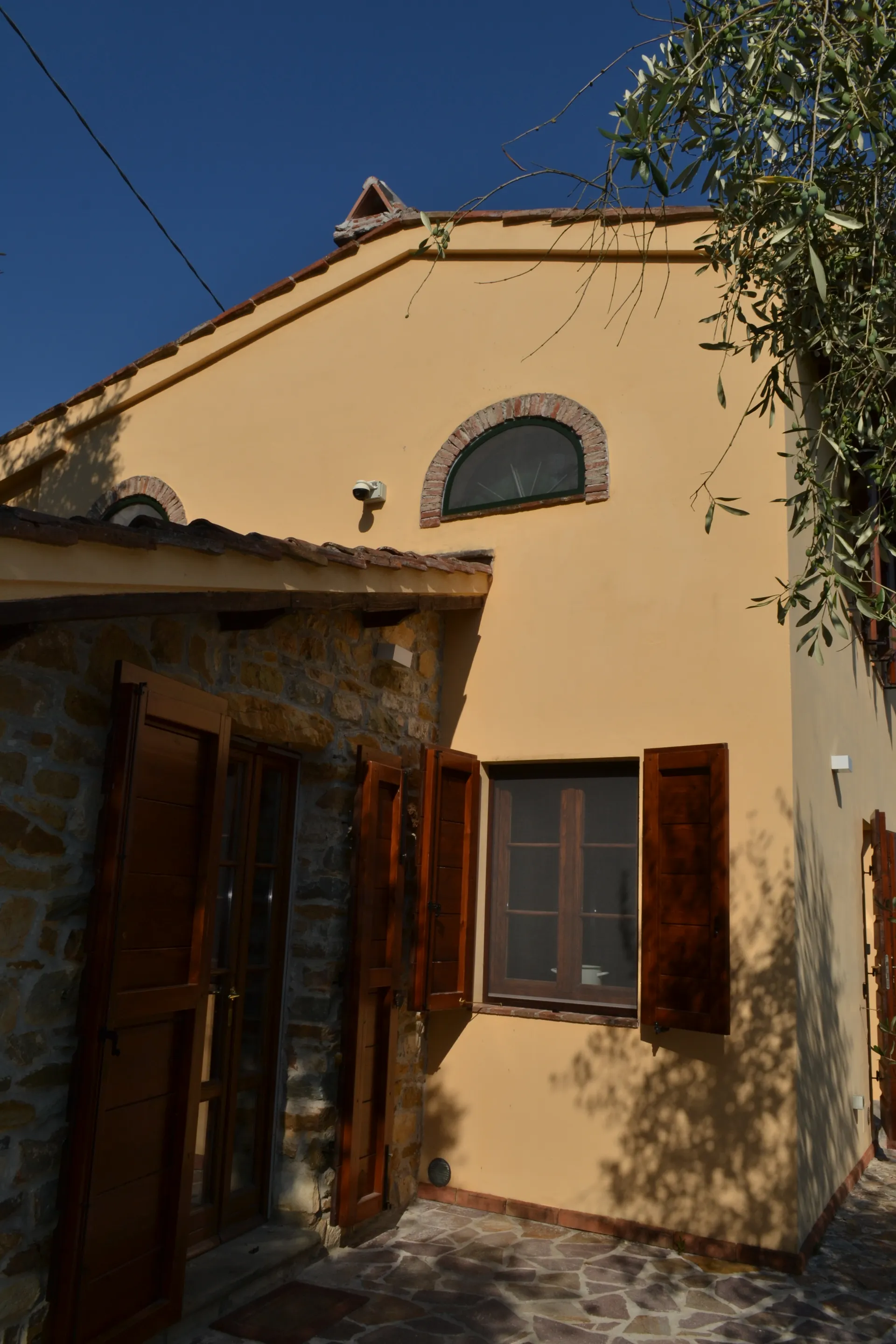 The ochre facade of Casale Eleo among the olive trees