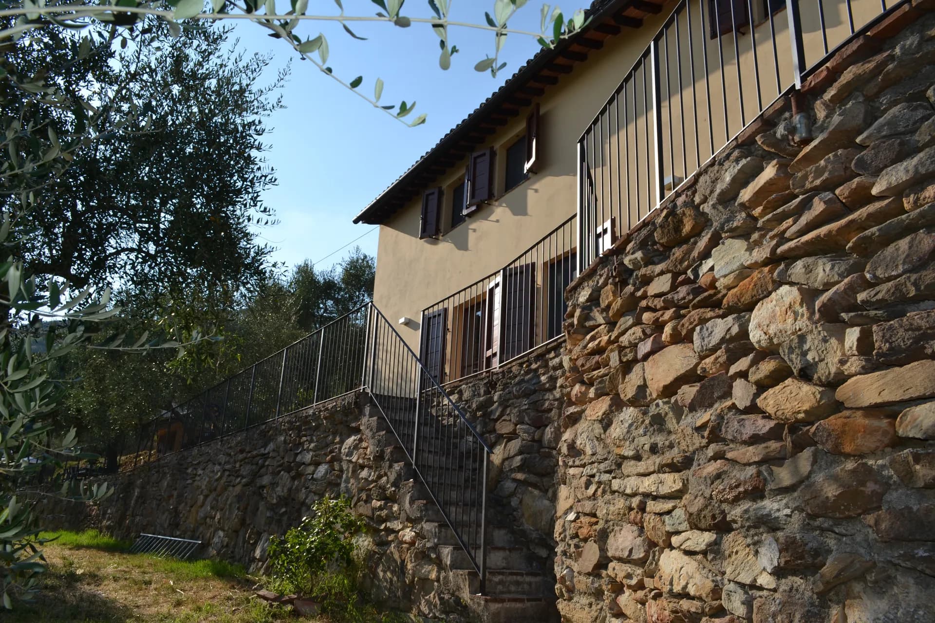 The ochre facade of Casale Eleo among the olive trees
