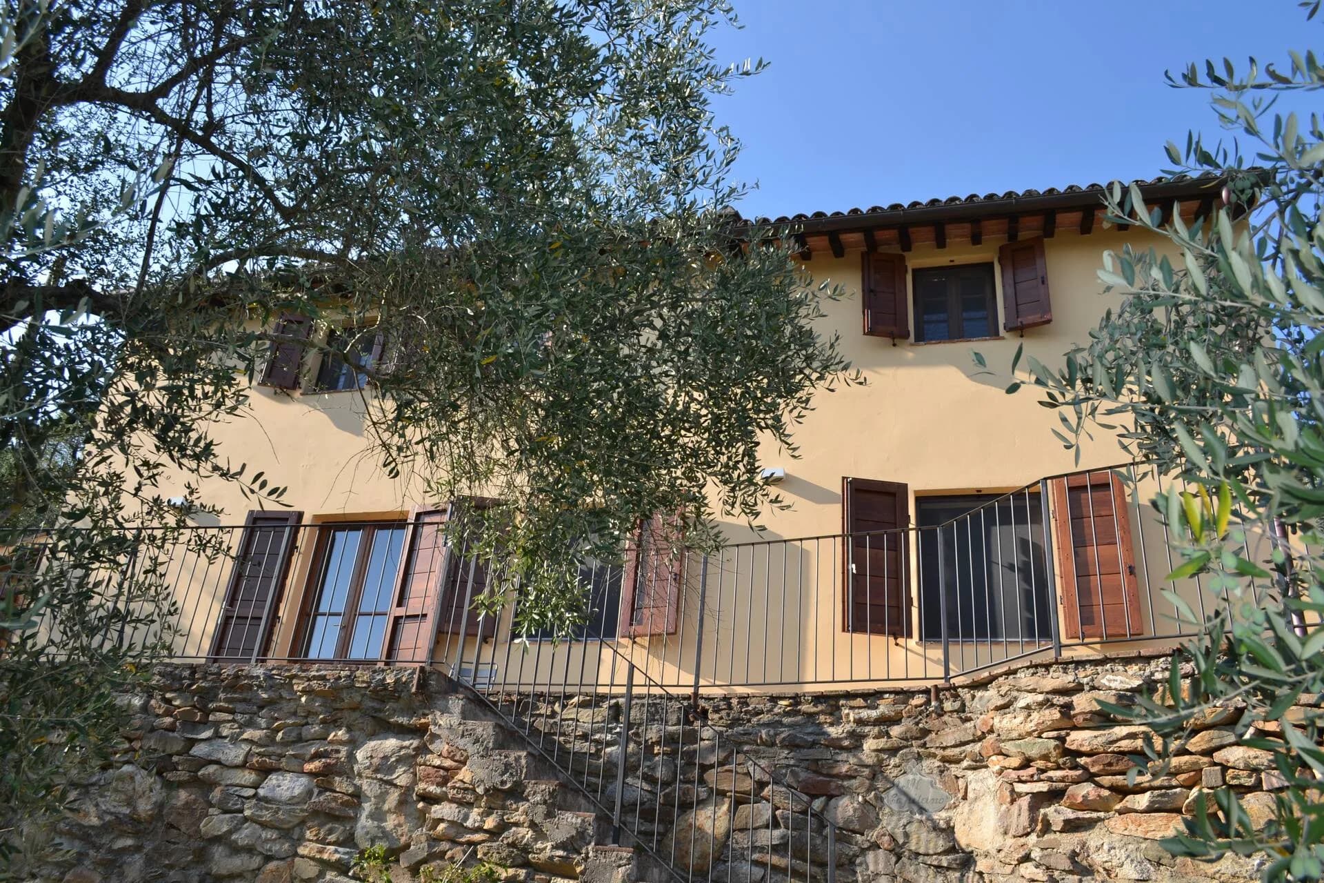 The stone farmhouse facade with terracotta roof and green shutters