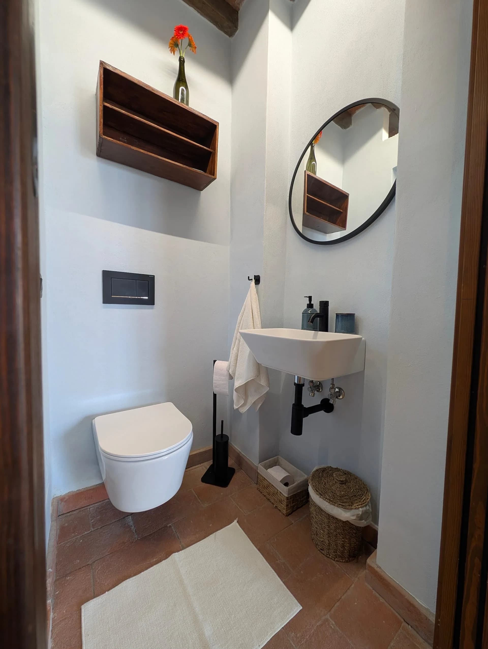 A guest bathroom with a wall-mounted basin and round mirror