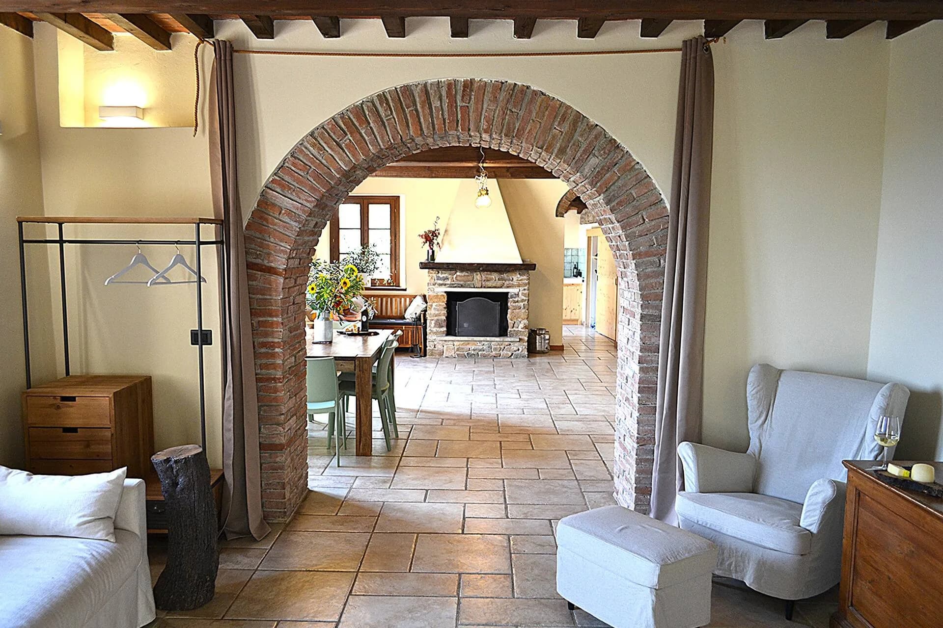 Dining table and stone fireplace seen through a brick archway