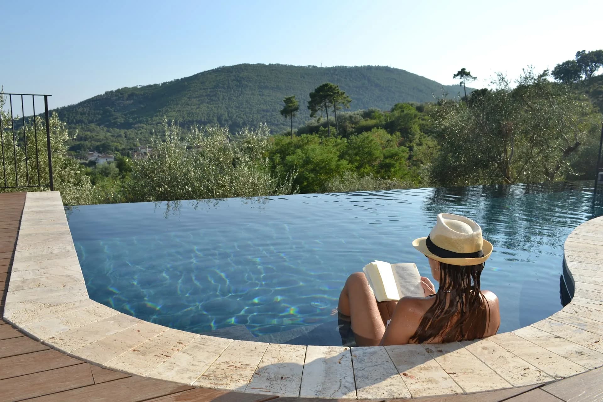 A guest reading at the edge of the infinity pool, looking over the valley