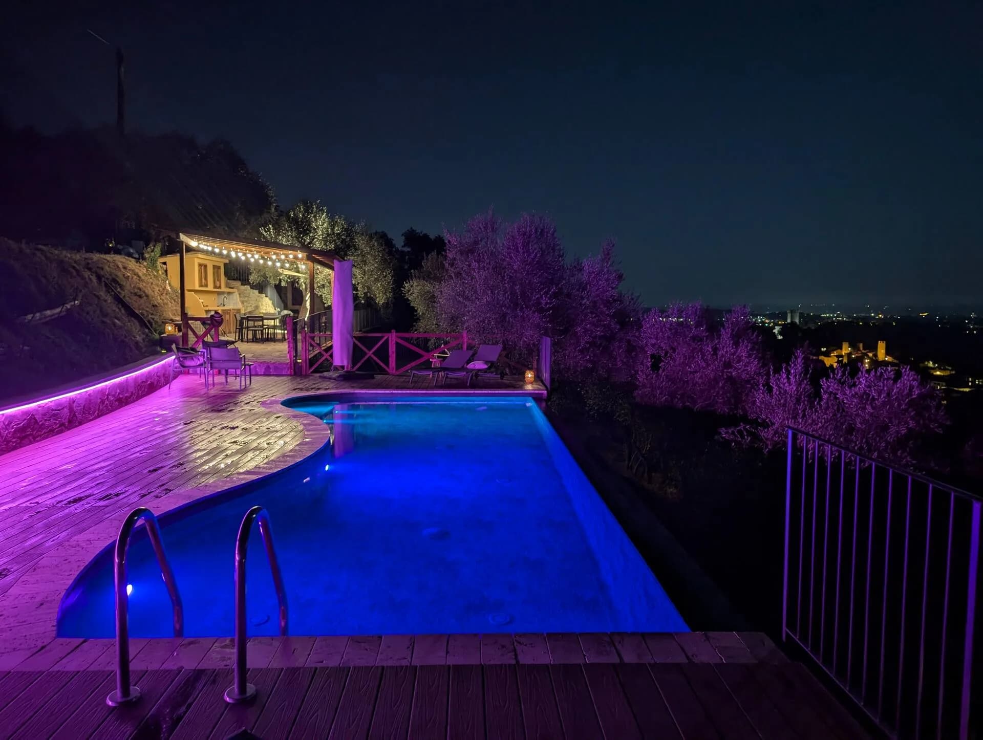 The infinity pool lit at night, with the valley lights below