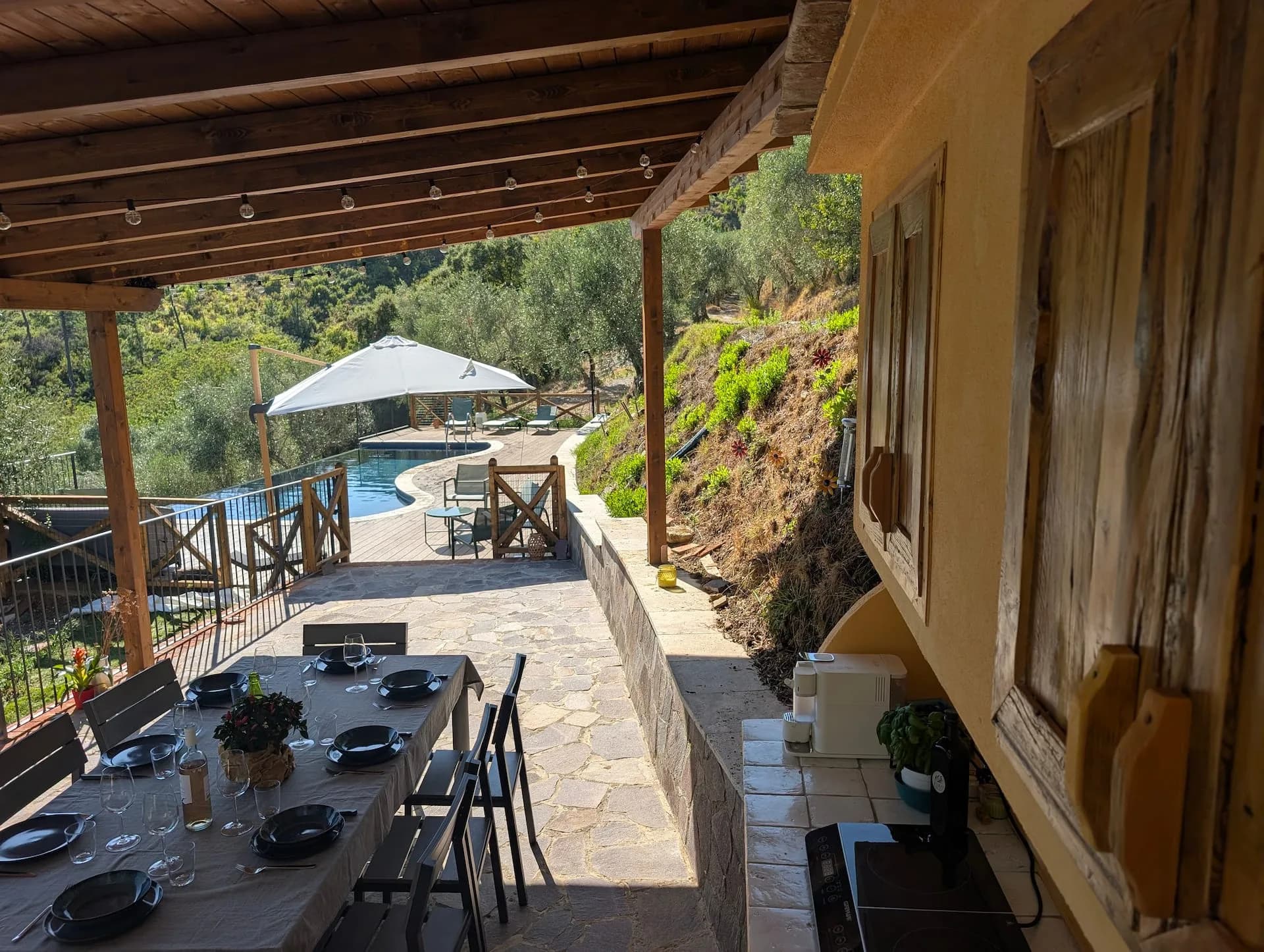 View from the covered terrace across the dining table to the pool and hills
