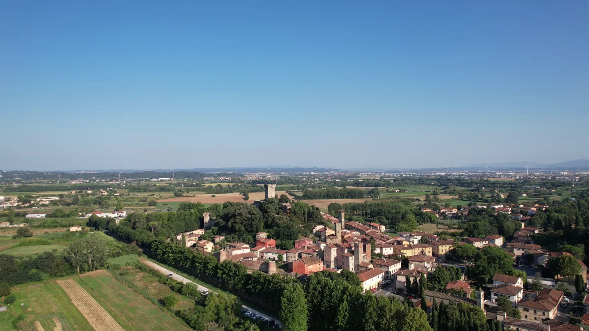Aerial view of Vicopisano's medieval towers rising above the rooftops, with the countryside beyond